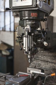 Old manual industrial drill iworking ina metal workshop