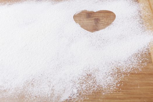 Flour shape heart in a mold on brown wood cutting board