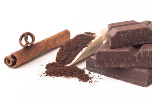 Cinamon stick and chocolate with some grounded coffe isolated on white background