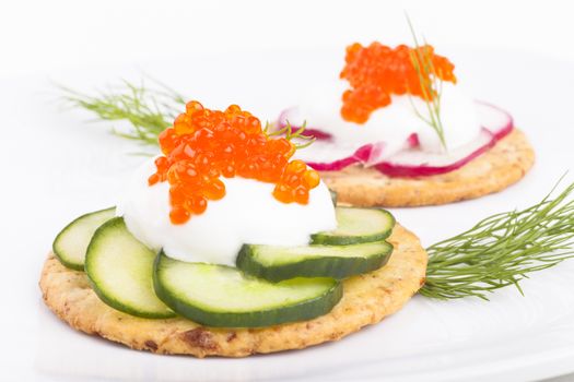 Red caviar on white chees and green cucumber appetiser on white background