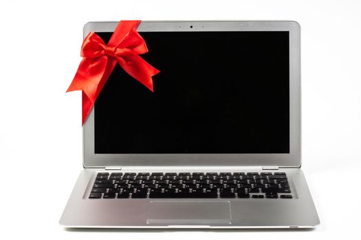 open silver laptop gift with red ribbon and black screen isolated on white background