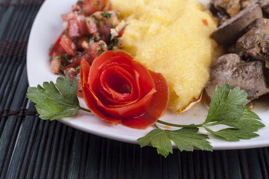 Red ornamental fllower close-up on food plate with healthy polenta dish
