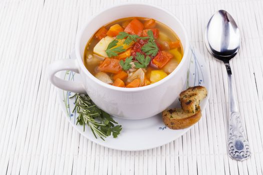 Vegetable spup in a bowl on white wood table and a spoon