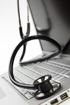 silver laptop diagnosis with black stethoscope crop closeup isolated on white background