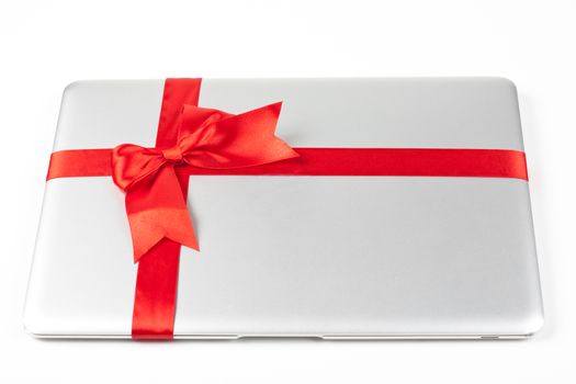 closed silver laptop gift with red ribbon isolated on white background