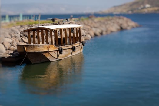 Single ancient boat on the see of galilee with reflection in the water