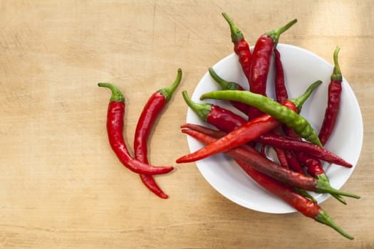 Red chili with one green cilli pepper in a bowl Two on wood background