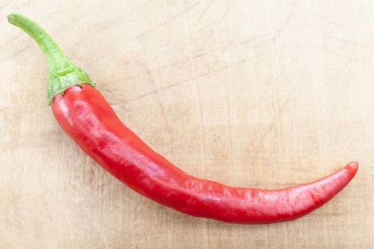 Single Red Hot Chili pepper on brown wood background