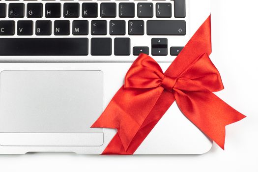 open silver laptop gift with red ribbon keyboard and trackpad closeup  isolated on white background