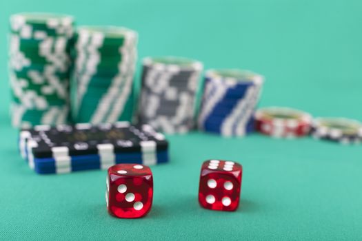 Red pair of dice on green with casino chips in the background