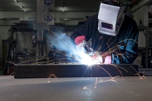 Welder with protective mask working in steel factory