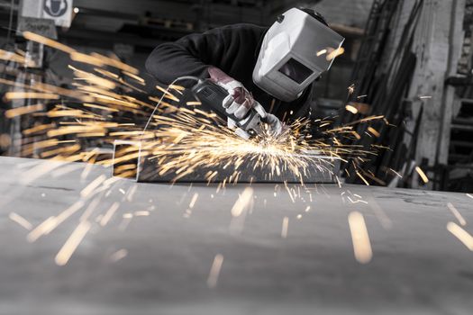 Heavy industry worker grinding with mask on the face 