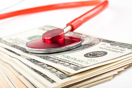 dollars cosulted with a red stethoscope close-up on white background
