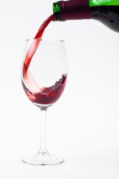 red wine puring from bottle to glass on white background