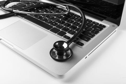 Silver laptop with black stethoscope on the keyboard side