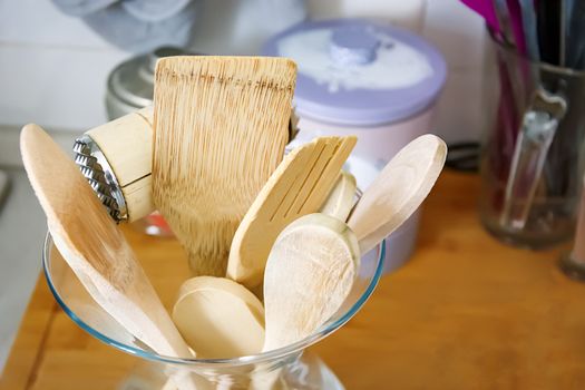 Wooden kitchen utensils in a glass container. Kitchen interior shot. Home decor and cooking concept