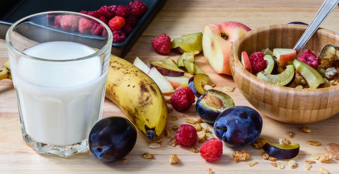 Muesli with sweet berries, fruits and milk - tasty and healthy superbreakfast. Scattered ingredients and slices of fruits.