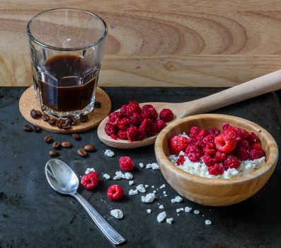 Cottage cheese with raspberries and cup of coffee for tasty breakfast. with scattered berries, grains of curd and coffee beans