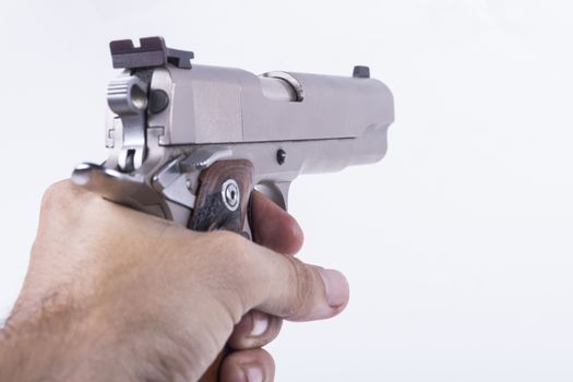 Hand holding silver colored gun isolated on white background