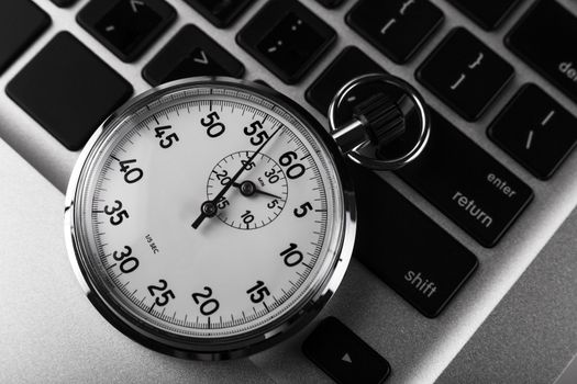 Silver stopwatch on silver laptop  keyboard closeup