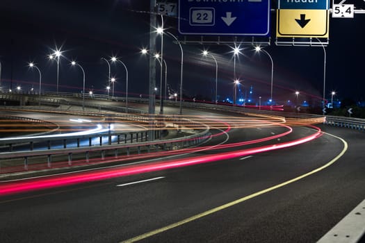  light trails on a highway passing vehicles light and road sign