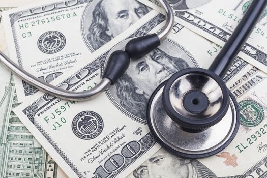 Black stethoscope close-up on top of Dollar banknotes