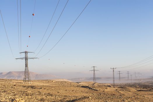 Electricity poles in the desert with mountains and fog in the valley