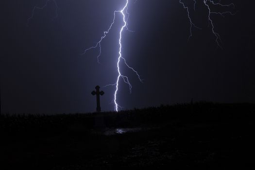 Lightning in a storm with a cross and reflection of the lightning