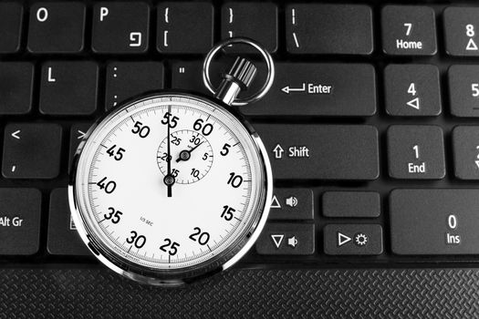 Silver stopwatch on black laptop keyboard in the background