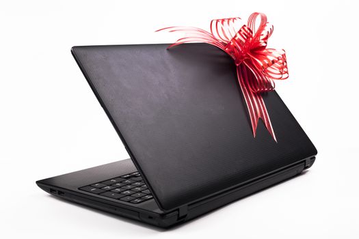 Black laptop half open with red  ribbon on the back of the screen isolated on white background