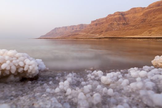 Dead sea lanscape with minehral structures on the shore and desert mountains in the background