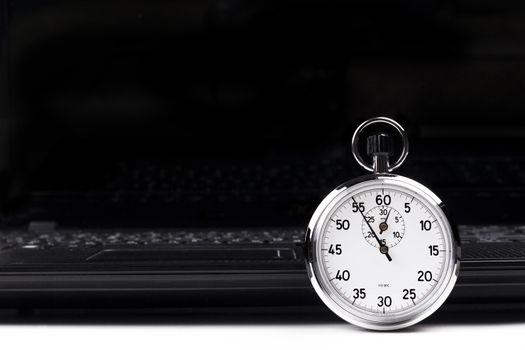 Silver stopwatch with black laptop in the background