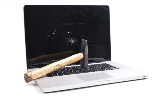 Broken laptop with smashed screen and a hammer isolated on white background