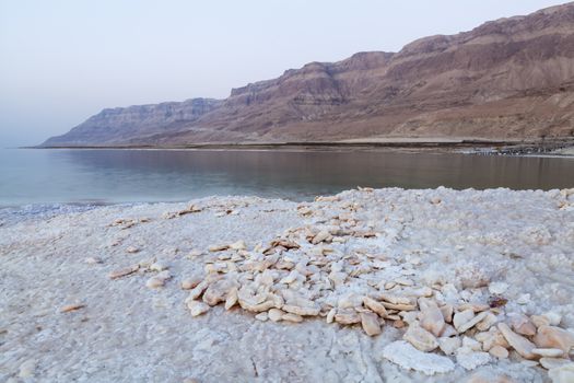 Stones made of salt on the dead sea shore with mountains in the backgrouns