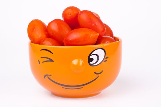 orange smiley face bowl fullwith red cherry tomato isolated on white background