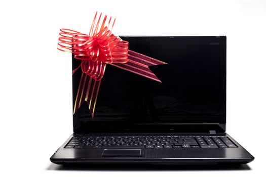 Black laptop with red ribbon gift isolated on white 