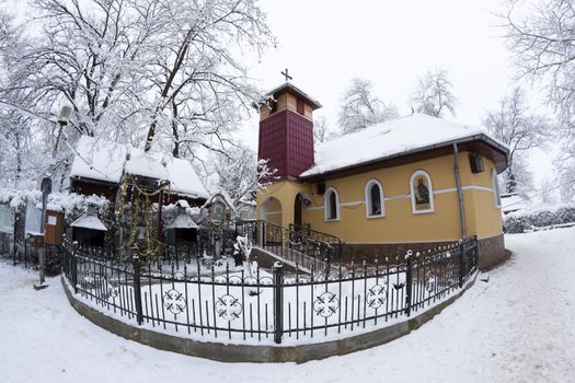 a small ortodox church covered with snow in the winter