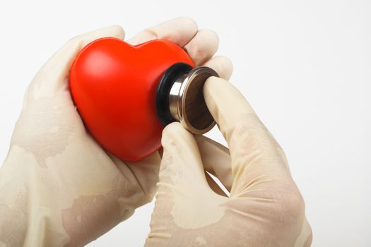 examining red heart hold in hand with a stethoscope on white background