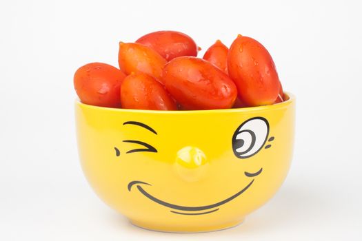 yellow smiley face bowl fullwith red cherry tomato isolated on white background