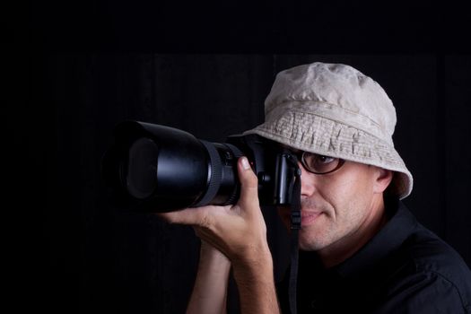 photographer with hat and big camebra on black background