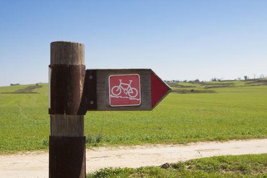 bycicle trail arrow sign on green grass background with blue sky