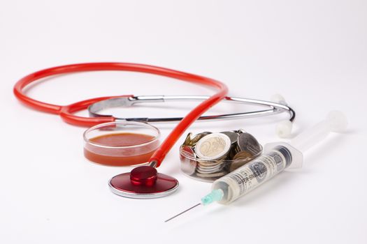 helthcare cost money coins and bills with a red stethoscope and blood sample