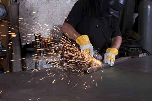 industrial grinding sparks with worker and protective mask and gloves