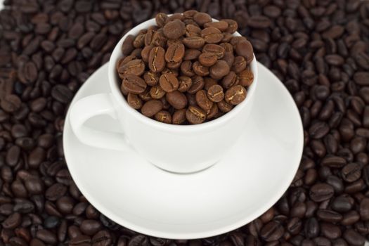 white coffee cup with plat eand coffee beans on dark beans background