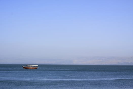 boat am the sea of galilee in a summer day with blue sky and water with the golan hight  in the background