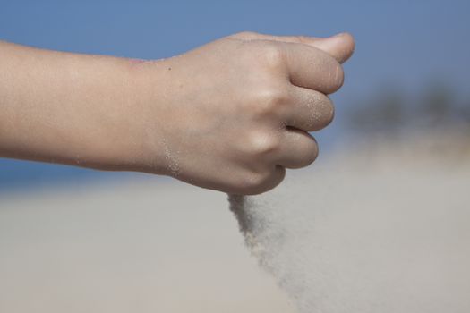 small girl hand pooring san from her fist