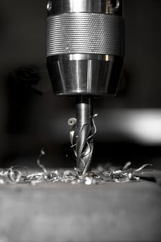 sharp metal dill in action drilling a hole in a metal plate