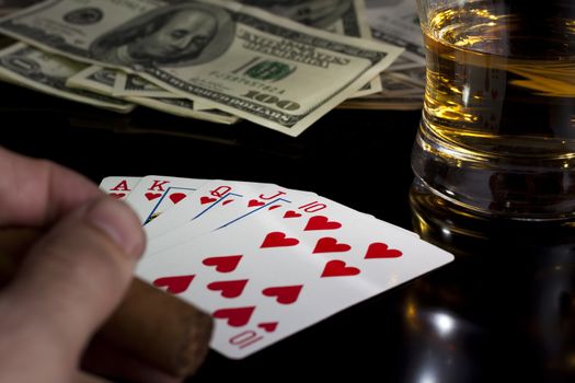 poker playing cards whiskey and some money on a table with reflection