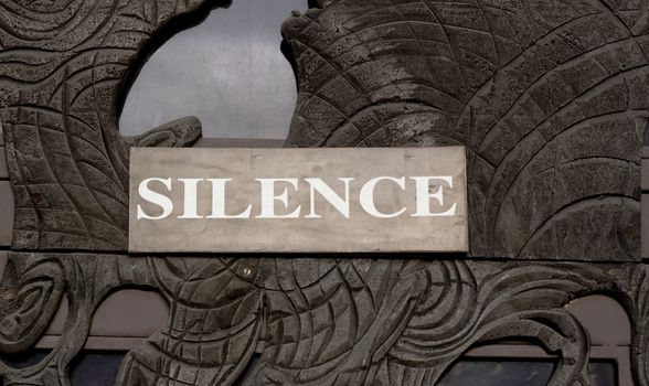silence sign on a door made of sculpured wood with glass