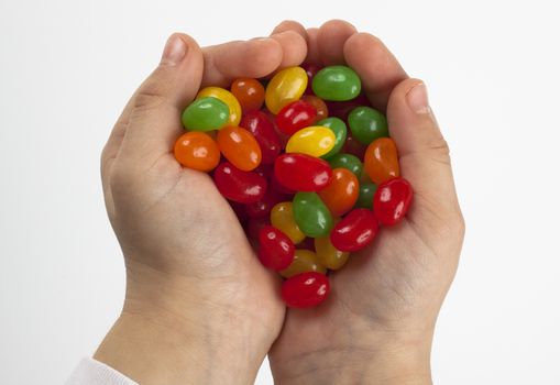 a pair of child hands holding a pile of colored candy